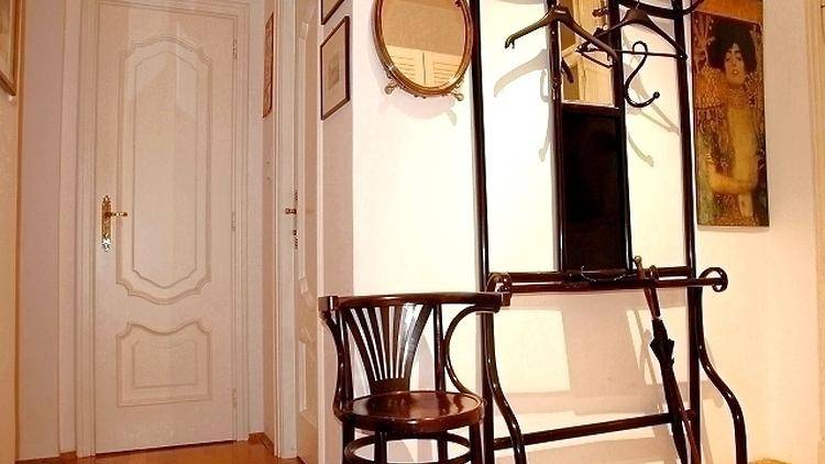 Heller Flur mit dekorativer Tür, Spiegel und Garderobe.