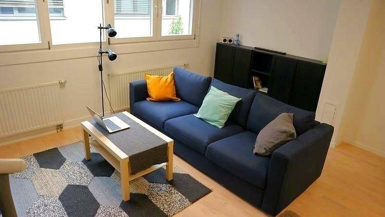 Moderner Wohnbereich mit blauem Sofa, Couchtisch und dekorativen Kissen in verschiedenen Farben.