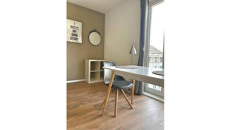 Essbereich im Schlafzimmer mit modernem Tisch, Stühlen und dekorativem Spiegel an der Wand.