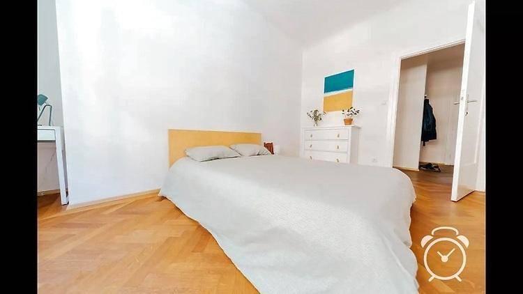Schlafzimmer mit Holzbett, Kommode und Zugang zu einem begehbaren Kleiderschrank.