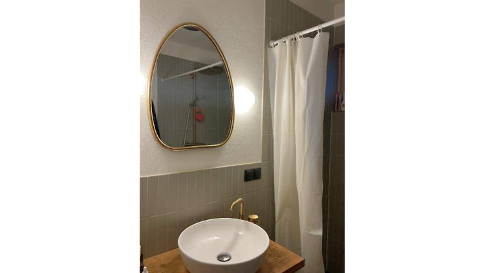 Modernes Badezimmer mit Waschbecken, Spiegel und Duschbereich.