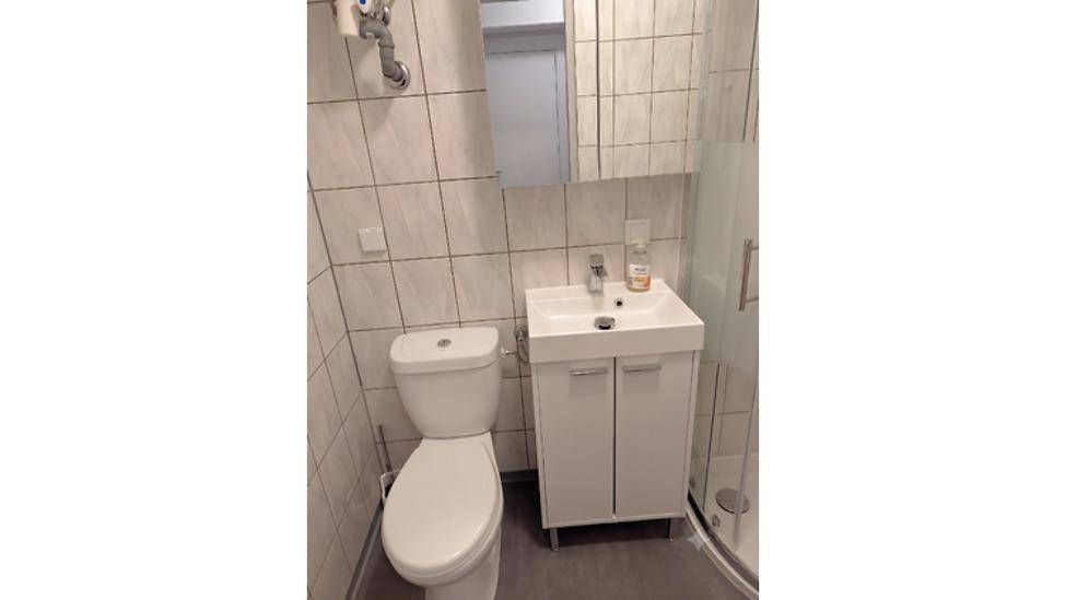 Modernes Badezimmer mit Toilette, Waschbecken und Duschkabine.
