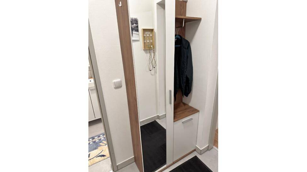 Eingangsbereich mit großem Spiegel, Garderobe und praktischer Ablage für Schuhe.