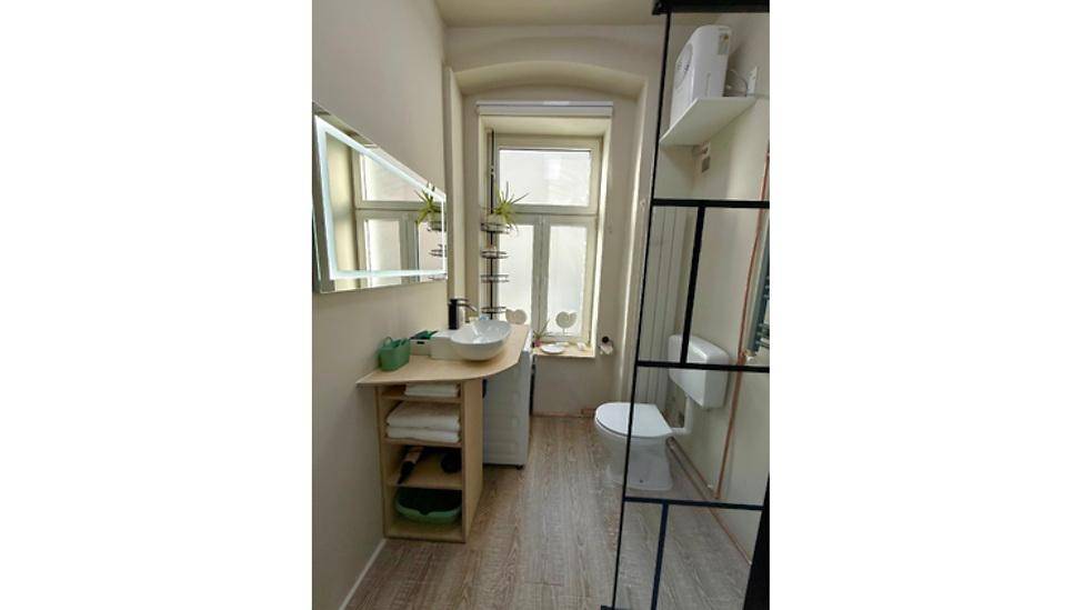 Modernes Badezimmer mit Waschbecken, Toilette und Fenster für natürliches Tageslicht.