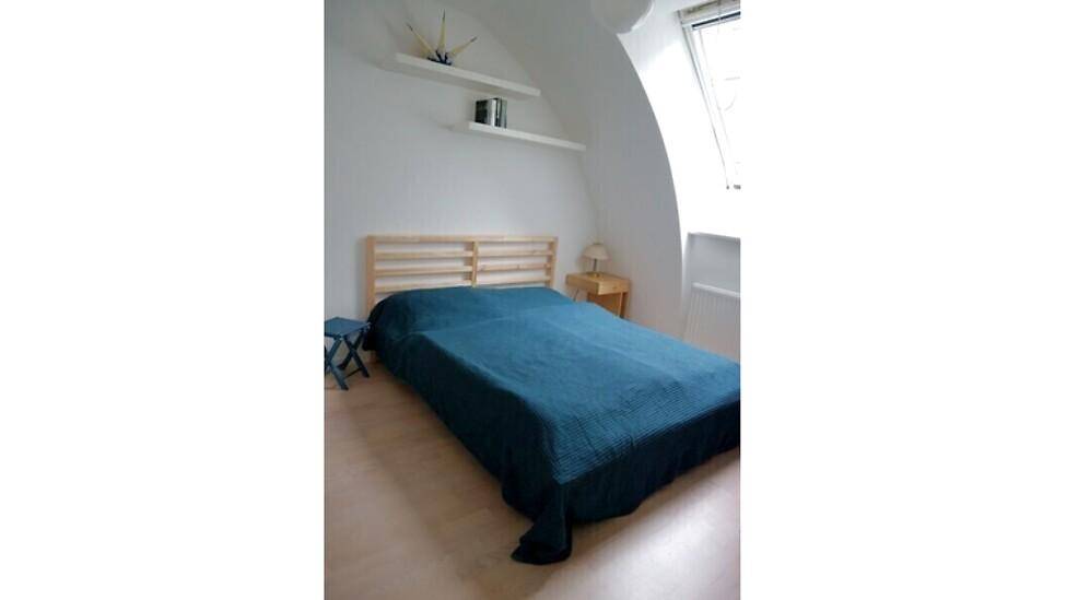Schlafzimmer mit Holzbett, Dachschräge und Dachfenster für eine helle Atmosphäre.