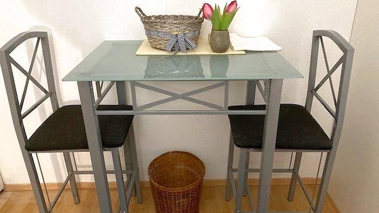 Kleiner Esstisch mit zwei Stühlen, dekoriert mit Blumen und einem Korb.
