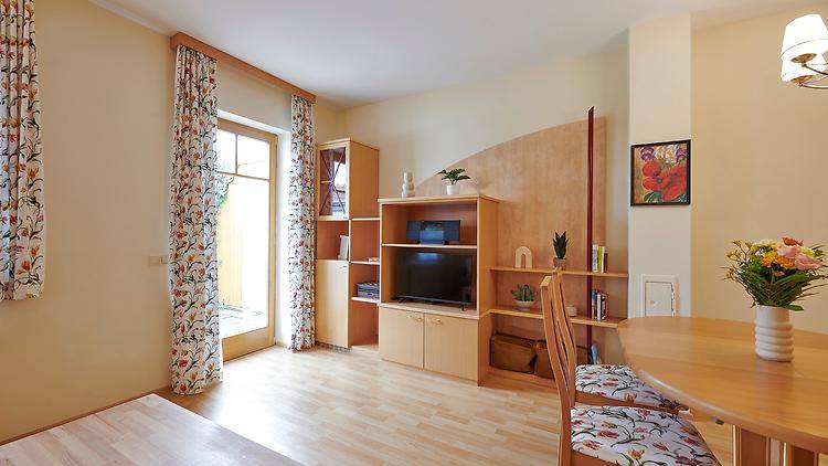 Heller Wohn- und Essbereich mit Holzmöbeln, Laminatboden und Zugang zum Garten.
