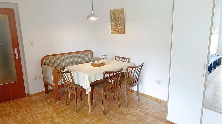 Gemütlicher Essbereich mit Holztisch, Sitzbank und Parkettboden.