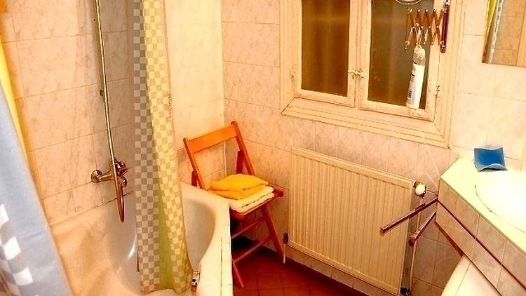 Badezimmer mit Badewanne, Duschvorhang, Heizkörper und einem Fenster.