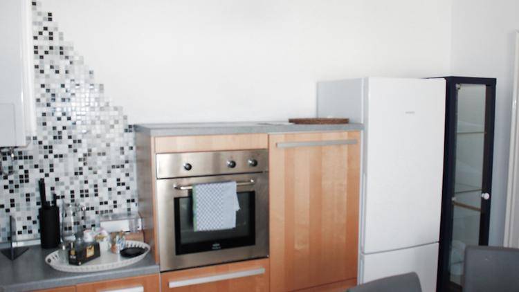Küchenzeile mit integriertem Backofen, Kühlschrank und einer dekorativen Mosaikfliesen-Rückwand.