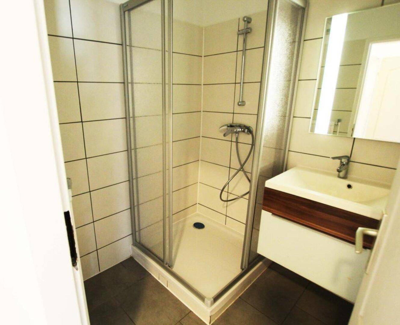 Modernes Badezimmer mit Duschkabine, Waschbecken und weißen Wandfliesen.