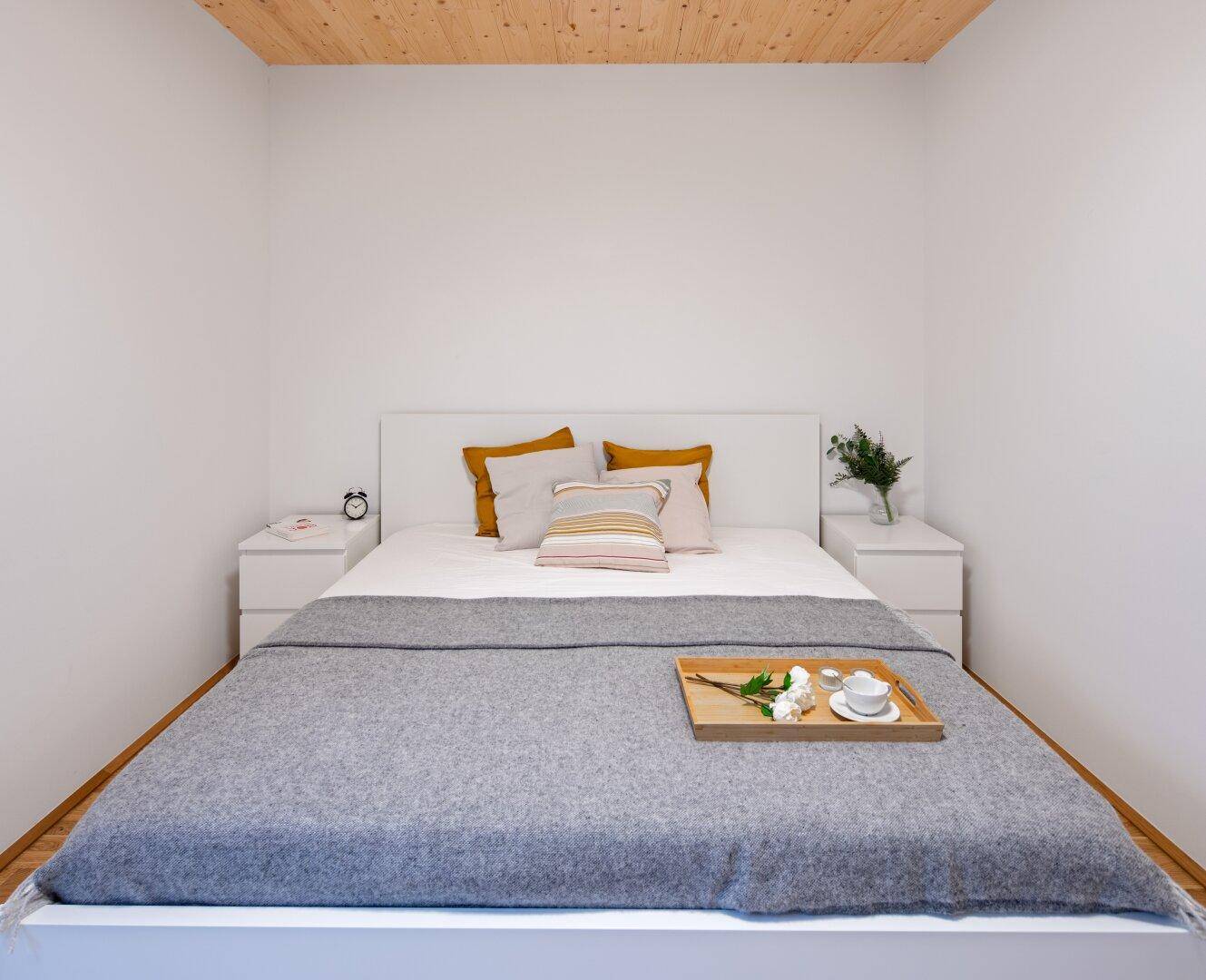 Modernes Schlafzimmer mit Doppelbett, Holzboden und minimalistischer Einrichtung.