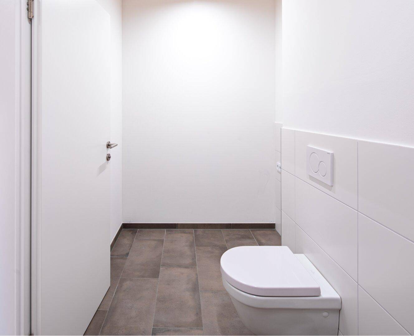 Modernes Gäste-WC mit Wand-WC und dunklen Fliesen auf dem Boden.