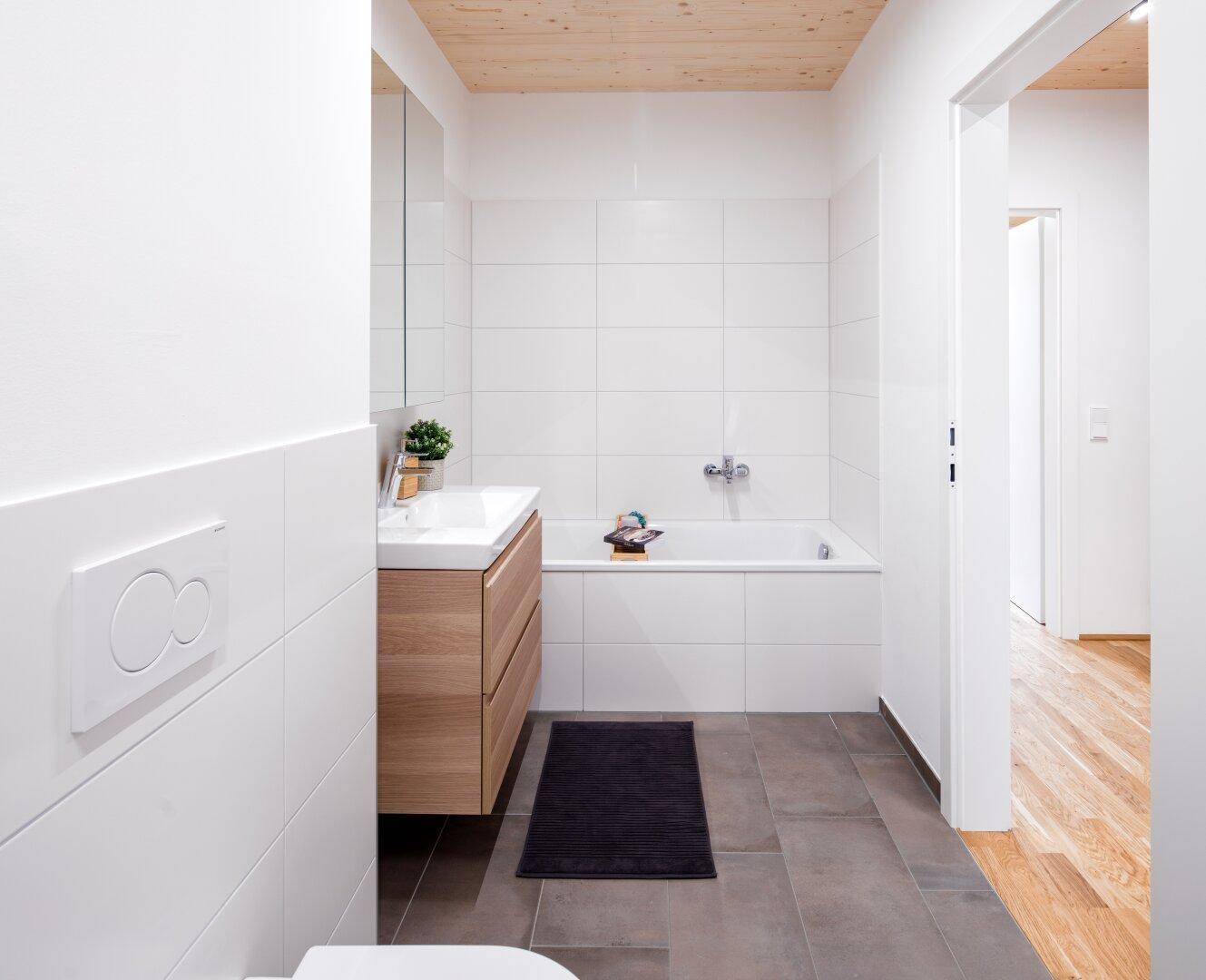 Modernes Badezimmer mit Badewanne, Waschtisch und weißen Wandfliesen.