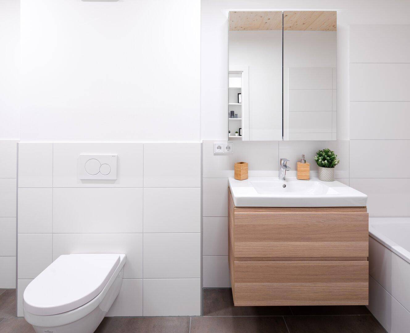 Helles Badezimmer mit Waschtisch, Wand-WC und Spiegelschrank.