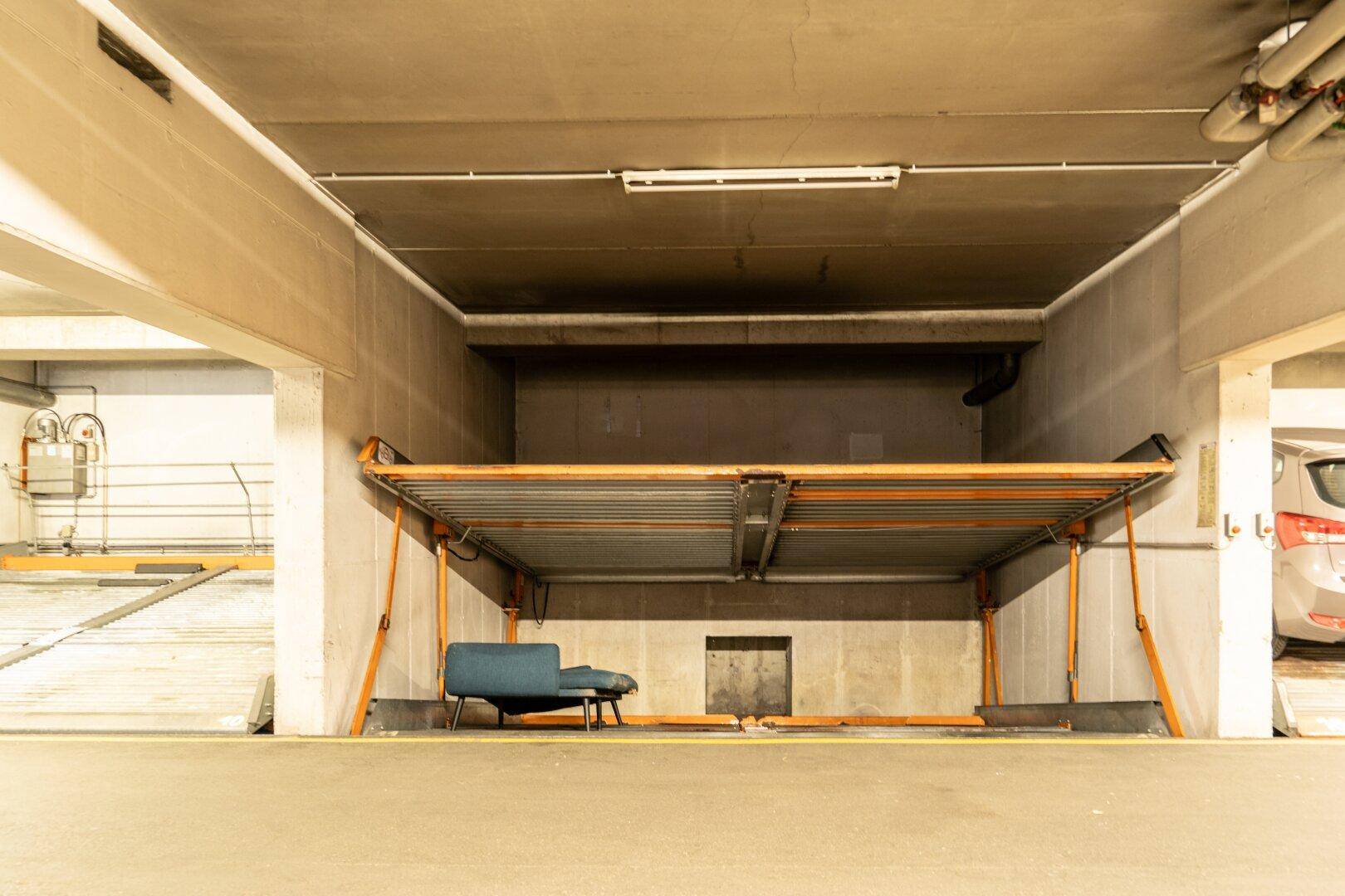 Ansicht des automatischen Parksystems in der Tiefgarage mit einem blauen Stuhl und Betonwänden.