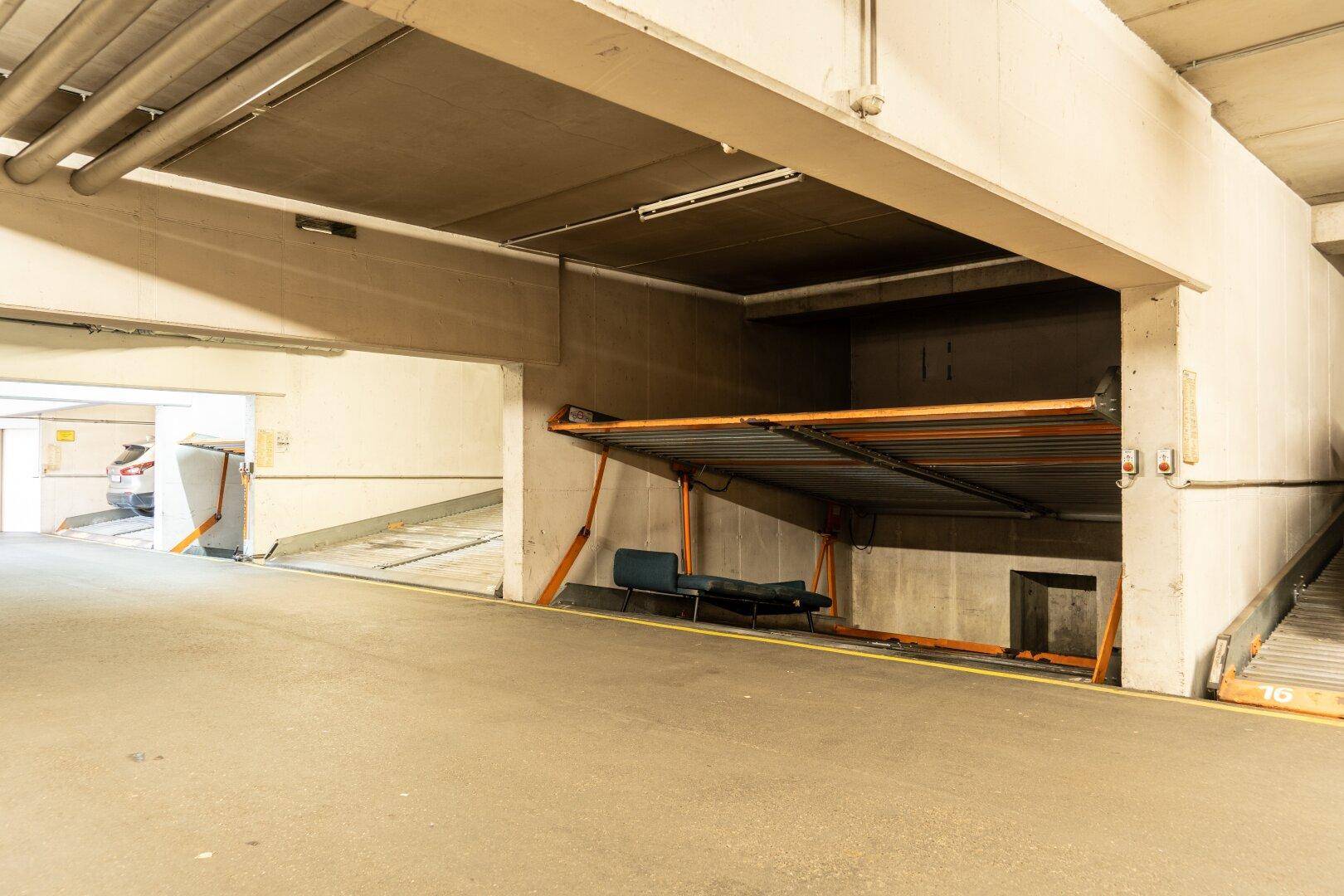 Tiefgarage mit automatischem Parksystem und einem blauen Stuhl aus einer anderen Perspektive.