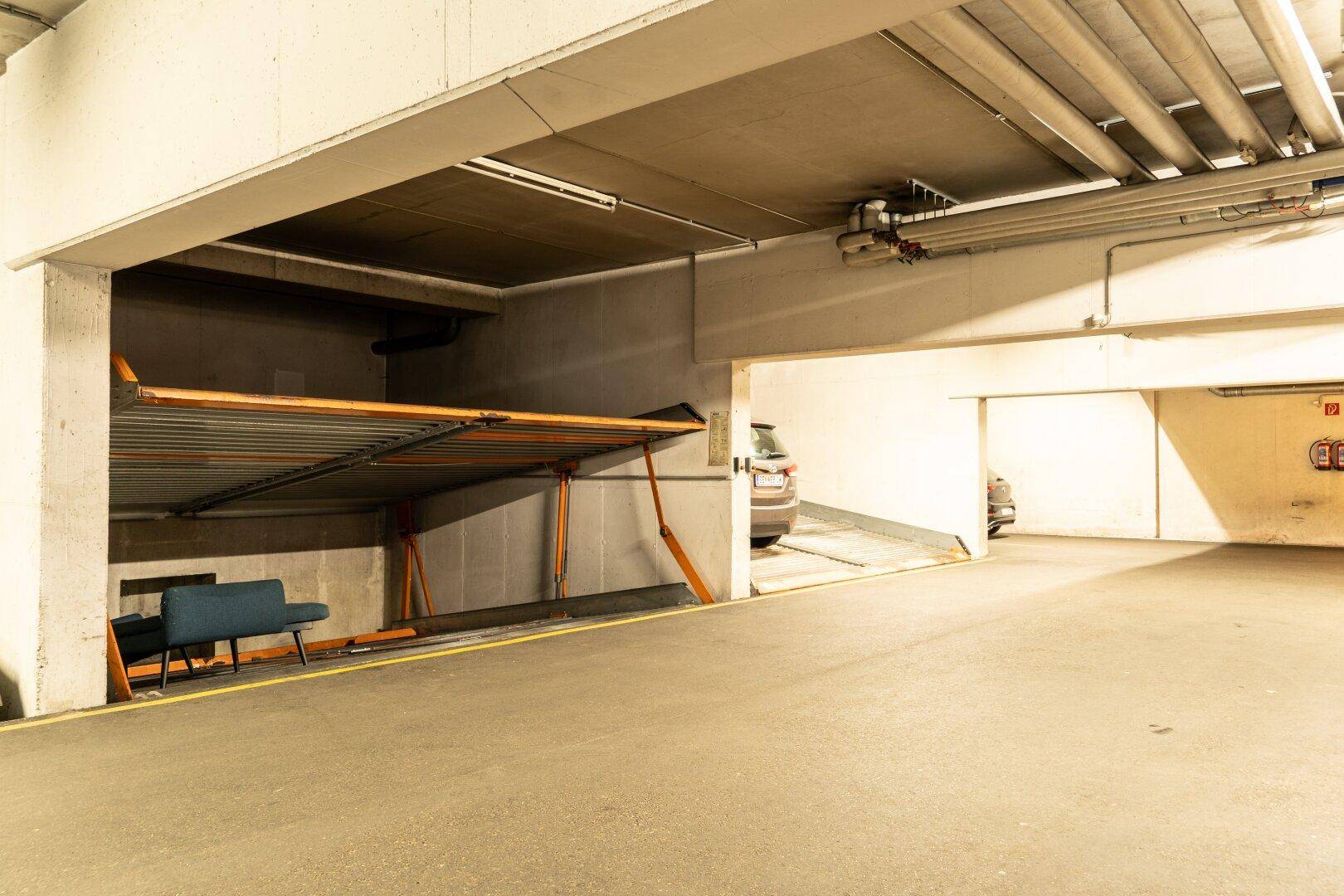 Tiefgaragenstellplatz mit mechanischem Parksystem und Blick auf die Ausfahrt der Tiefgarage.