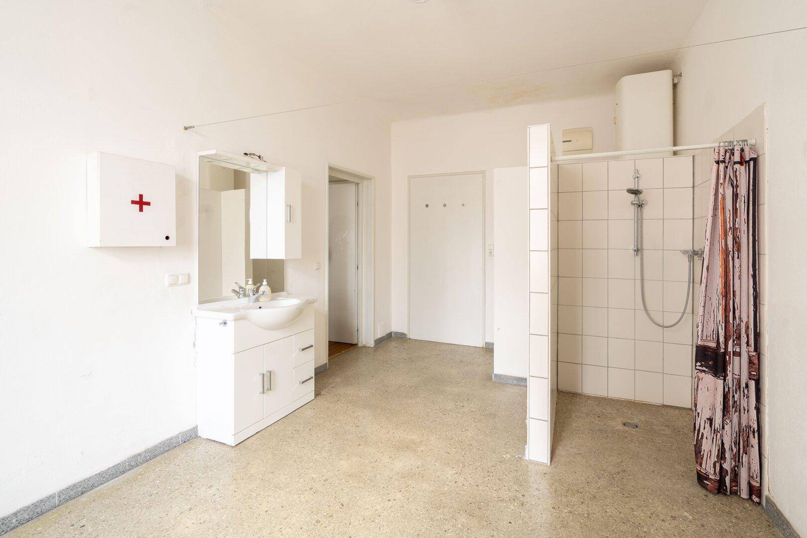 Geräumiges Badezimmer mit Waschbecken, Spiegelschrank und einer Duschkabine mit Vorhang.