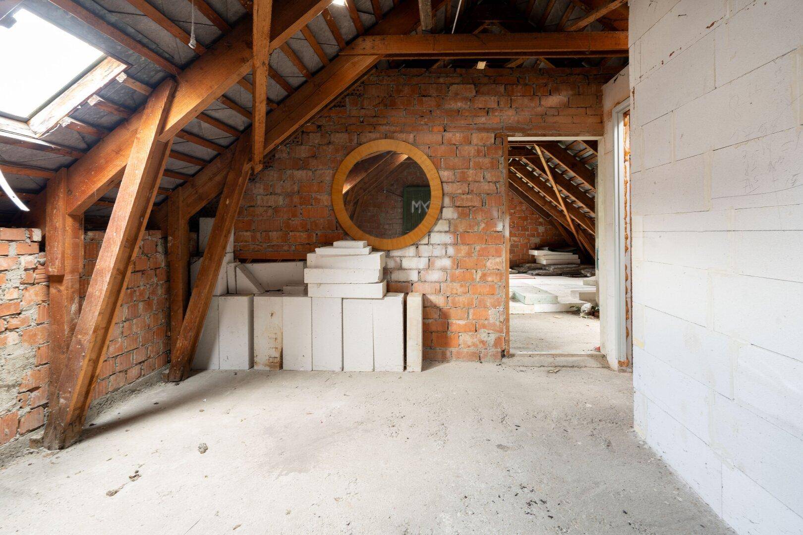 Dachboden im Rohbau mit sichtbaren Holzbalken und Ziegelwänden, bereit zum Ausbau.