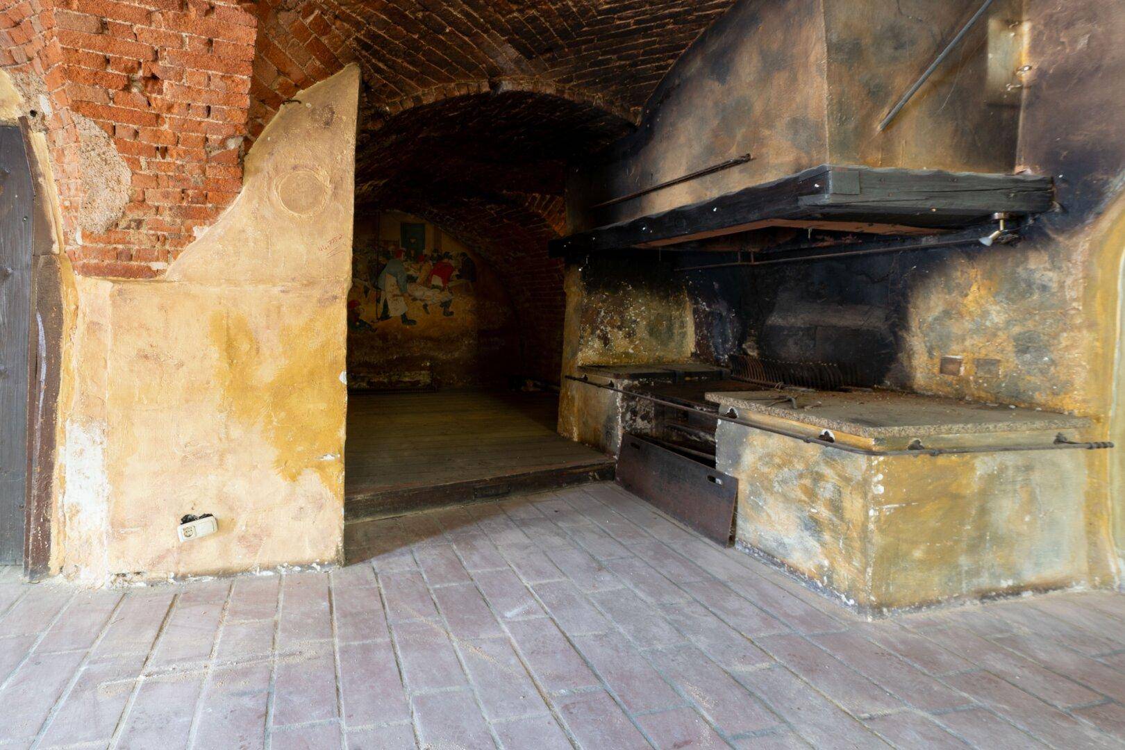 Historischer Gewölbekeller mit Ziegelgewölbe, altem Kamin und rustikalem Ambiente.