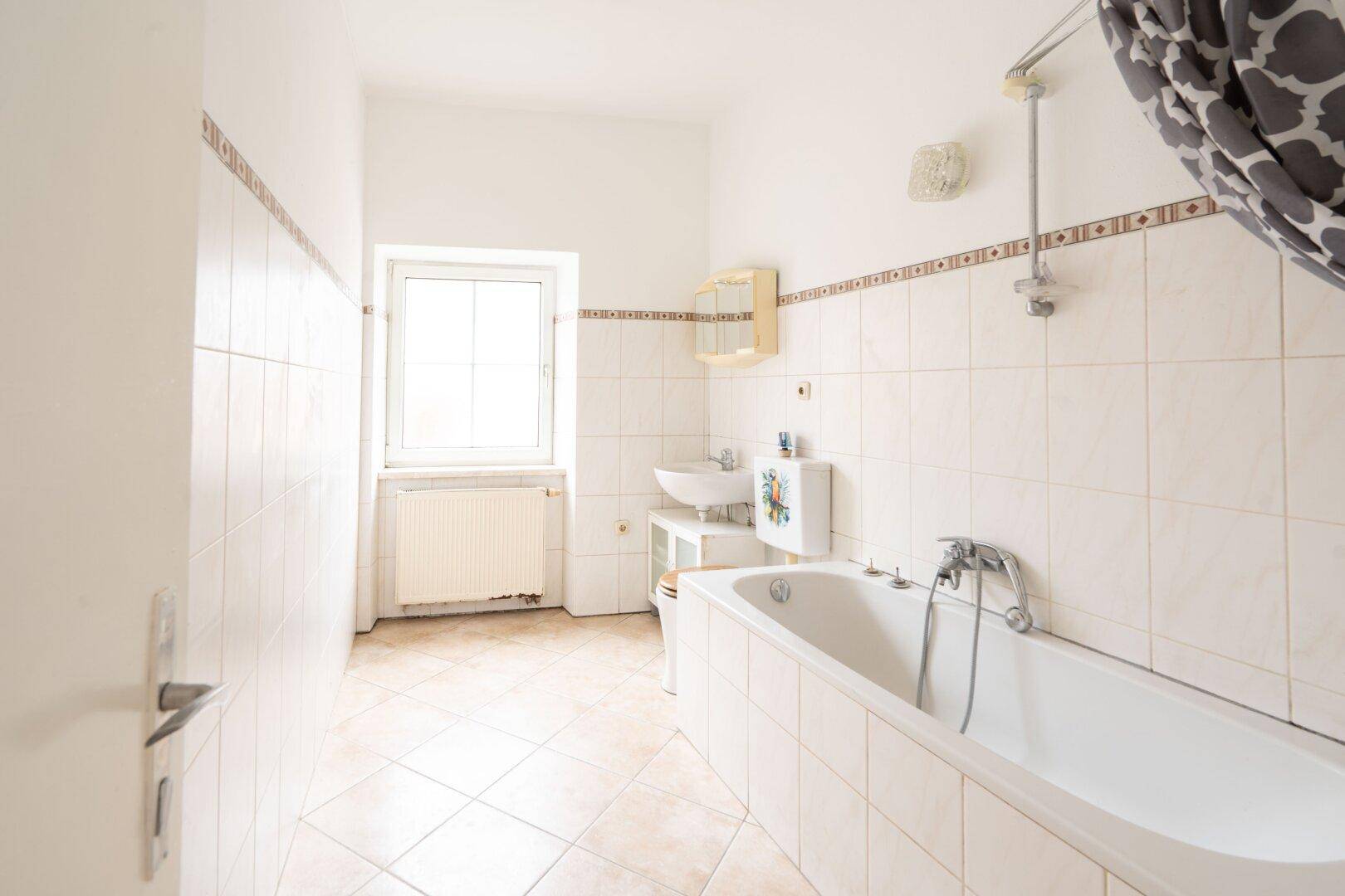 Helles Badezimmer mit Badewanne, Waschbecken und Fliesen in Beige- und Brauntönen.