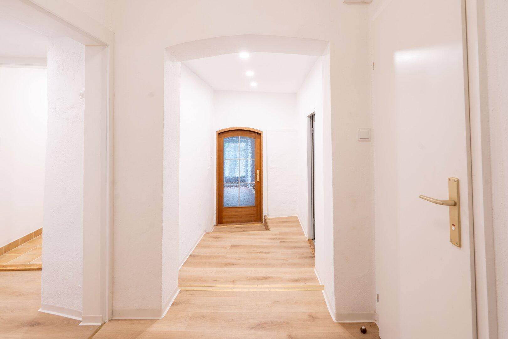 Heller Flur mit Holzlaminatboden und modernen Einbaustrahlern in der Decke.