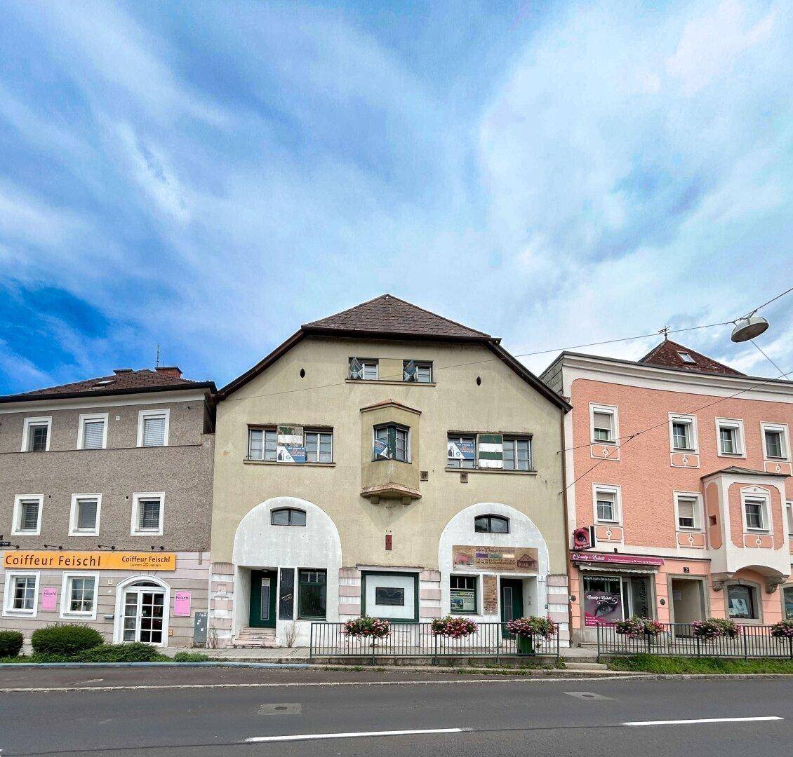 Historische Fassade eines Gebäudes mit Geschäften im Erdgeschoss und Wohnungen darüber.