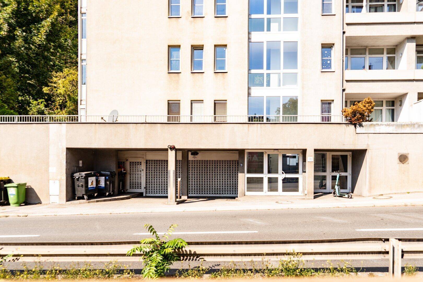 Fassade eines modernen Mehrfamilienhauses mit großen Fenstern und ebenerdigen Eingängen von der Straße aus.