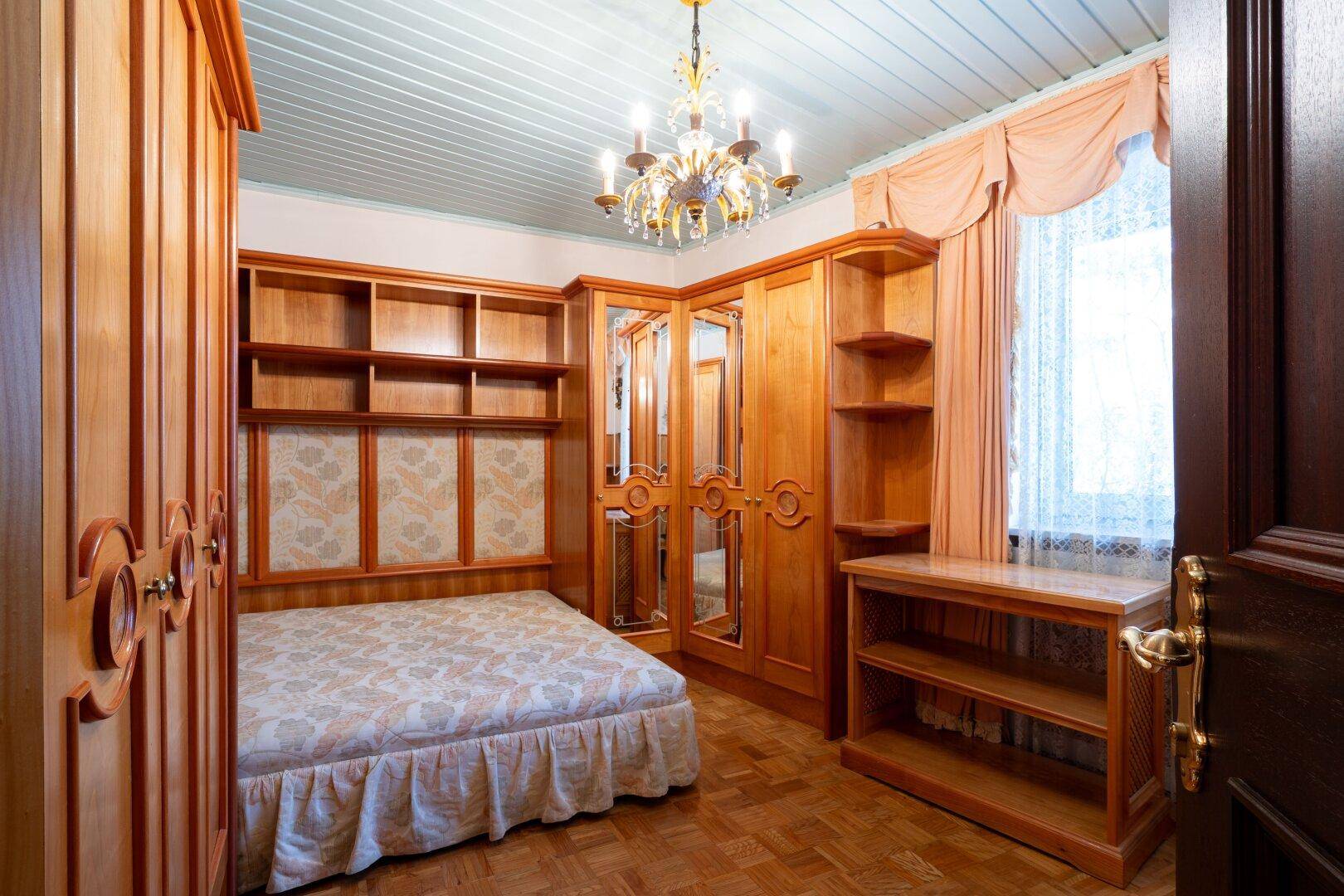 Schlafzimmer mit maßgefertigten Holzmöbeln, Parkettboden und einem klassischen Kronleuchter.