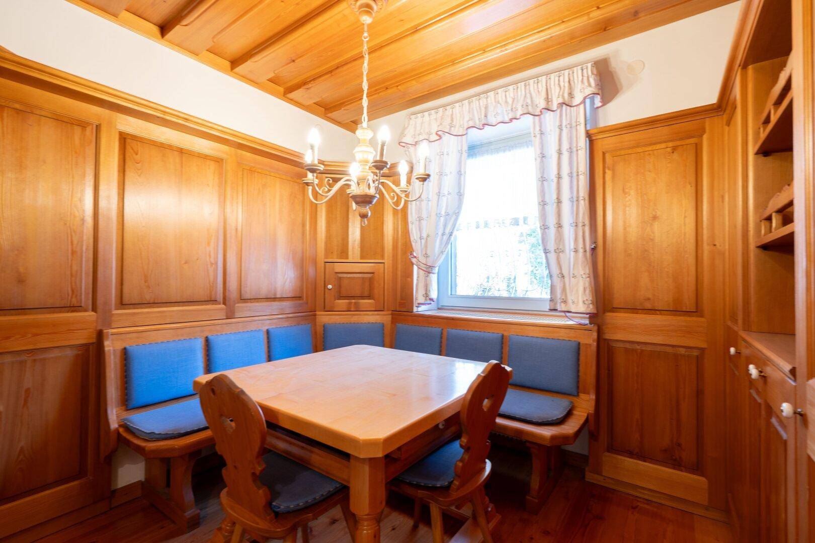Traditionelle Essecke mit Holztäfelung, blauen Sitzpolstern und rustikalem Charme, perfekt für gesellige Runden.