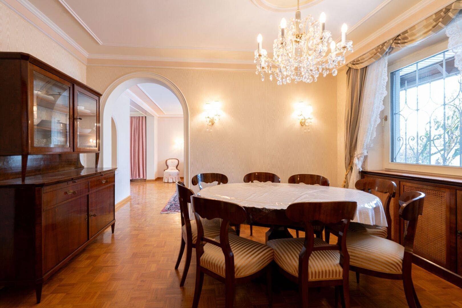 Eleganter Essbereich mit Parkettboden, Kronleuchter und klassischem Mobiliar, ideal für formelle Anlässe.