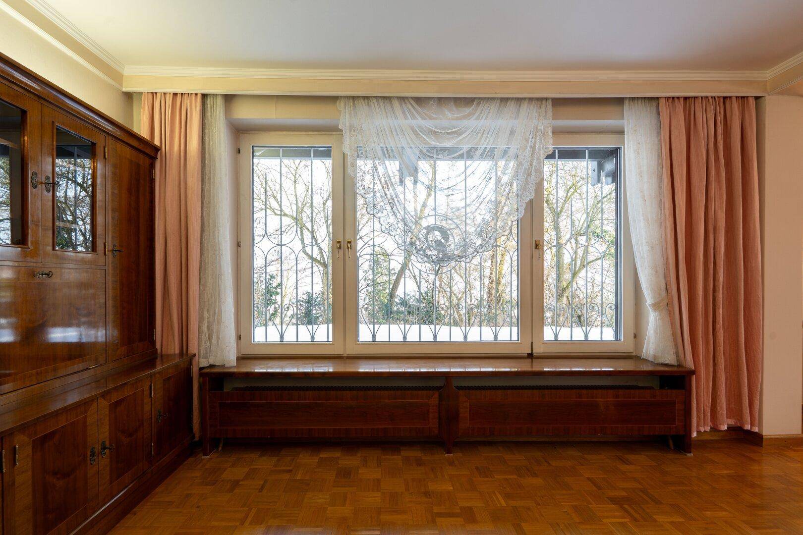 Helles Wohnzimmer mit großen Fenstern und Blick ins Grüne, das eine ruhige Atmosphäre schafft.