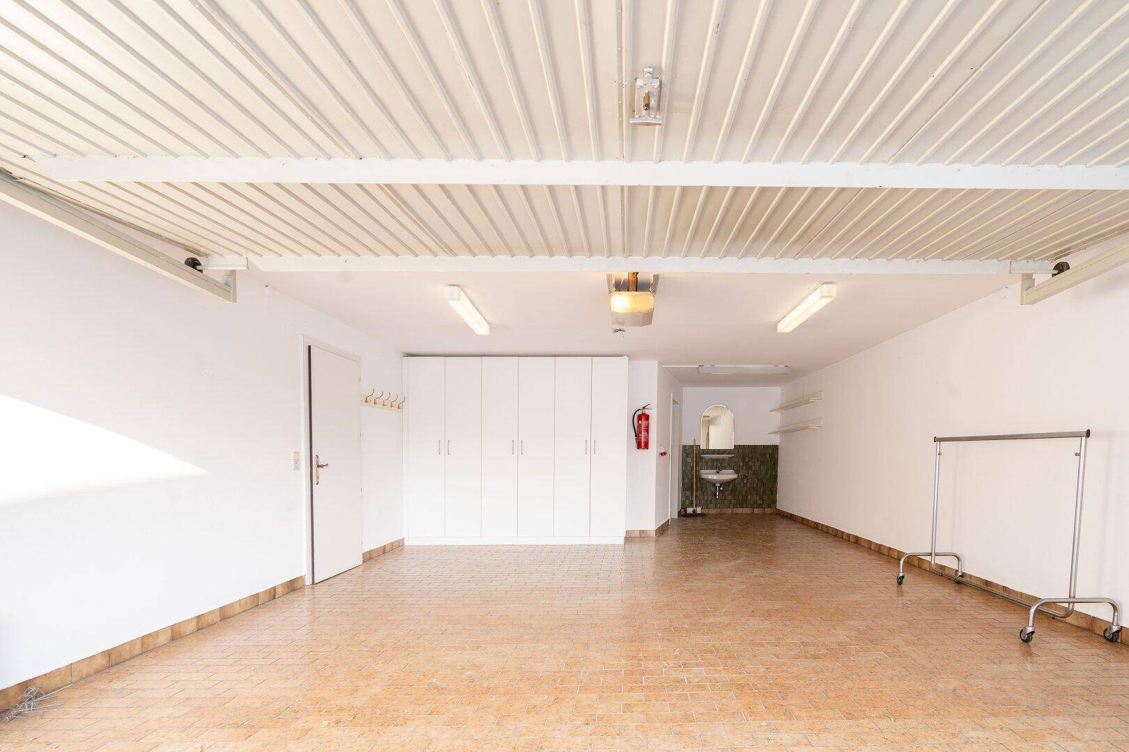 Geräumige Garage mit Stauraum, Waschbecken und Fliesenboden, die viel Platz bietet.