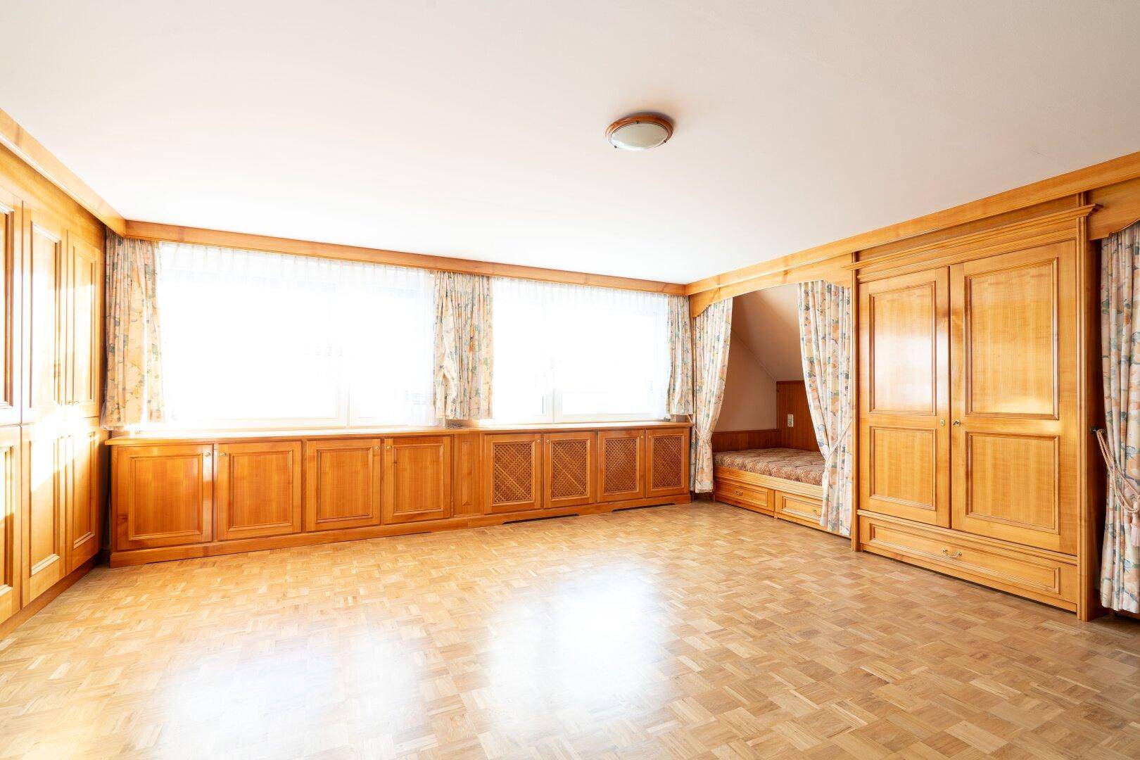 Geräumiges Zimmer mit Einbauschränken aus Holz und Parkettboden, das viel Stauraum bietet.