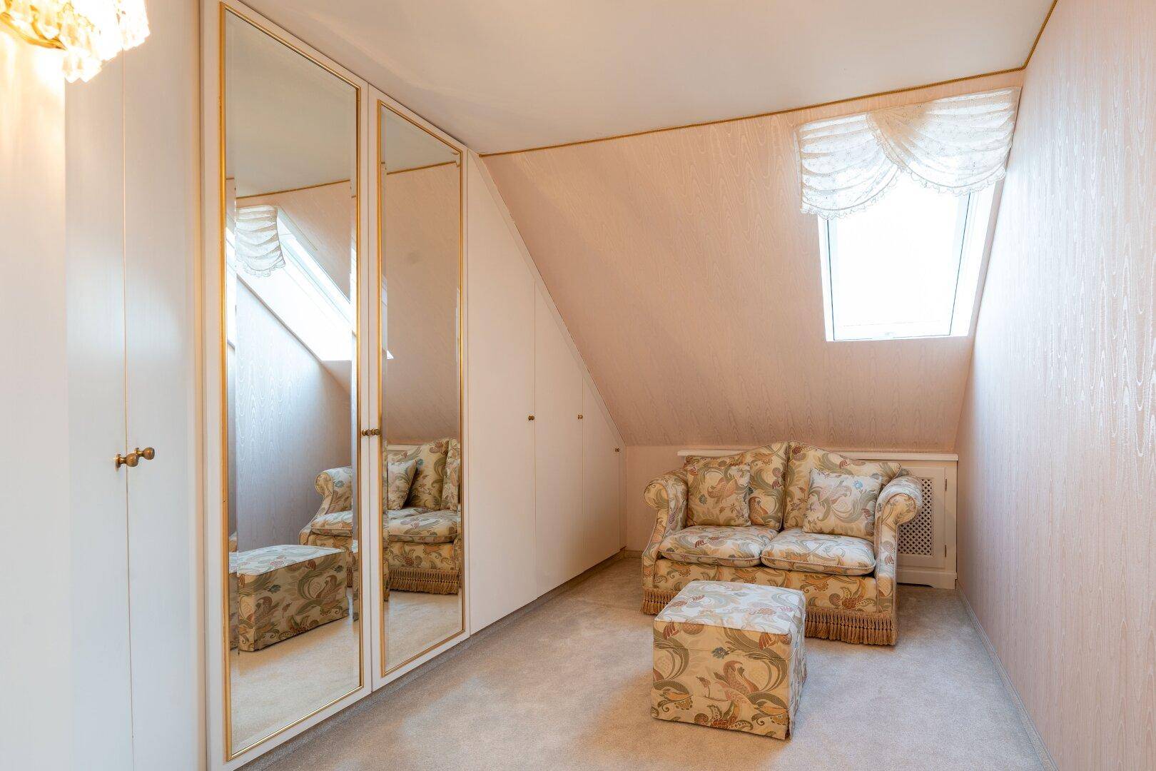 Heller Flur im Dachgeschoss mit Spiegelschränken und Dachfenster, das den Raum mit Licht durchflutet.