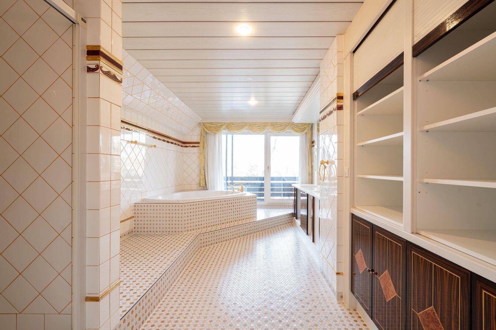 Geräumiges Badezimmer mit Badewanne, Einbauregalen und Zugang zum Balkon, der eine entspannende Atmosphäre bietet.