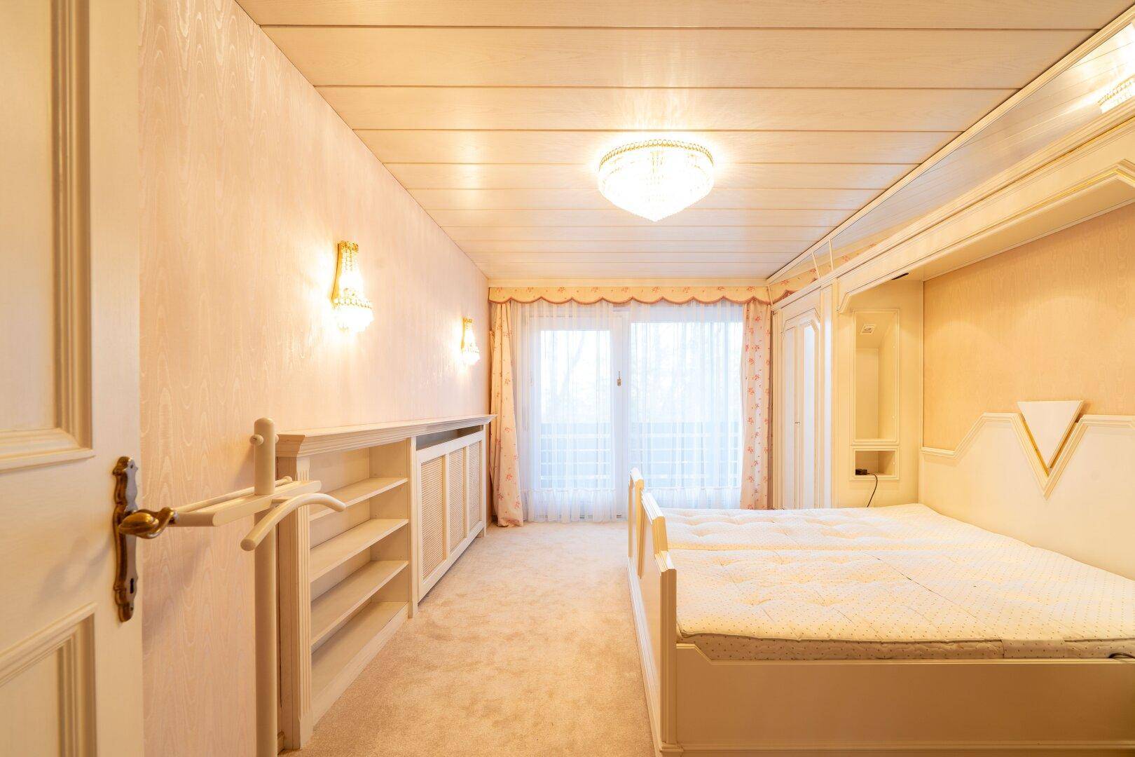 Schlafzimmer mit Einbaubett, Teppichboden und Zugang zum Balkon, der eine private Rückzugsmöglichkeit bietet.