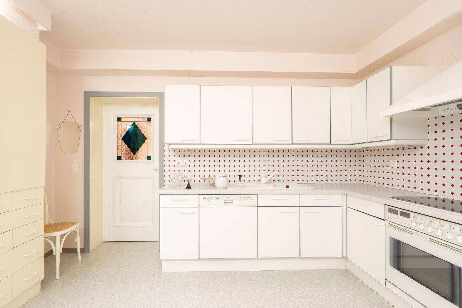 Moderne weiße Küche mit Einbaugeräten, Fliesenrückwand und hellem Ambiente, die Funktionalität und Stil vereint.