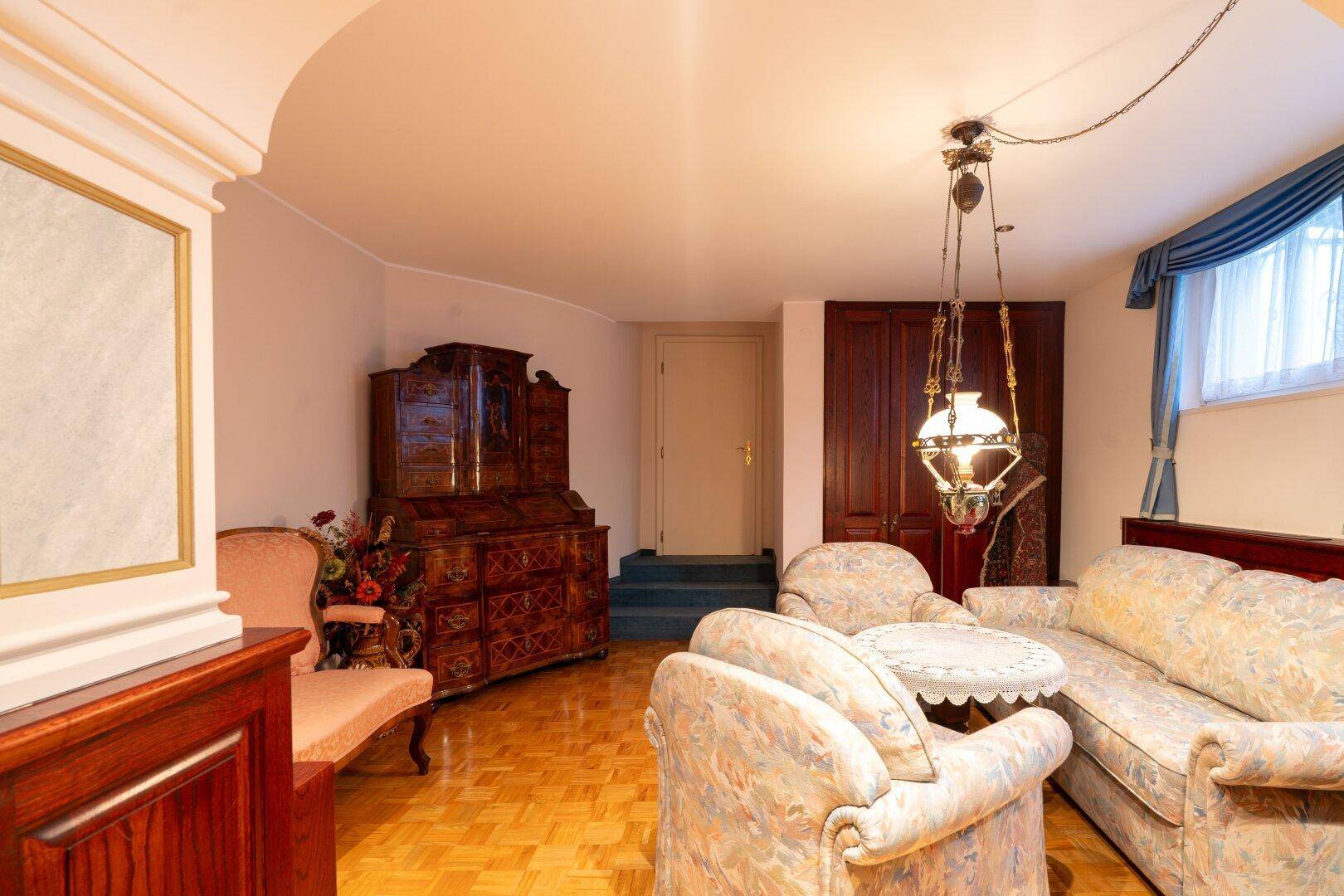 Wohnbereich im Keller mit Sofas, Couchtisch und traditioneller Einrichtung, perfekt für entspannte Abende.