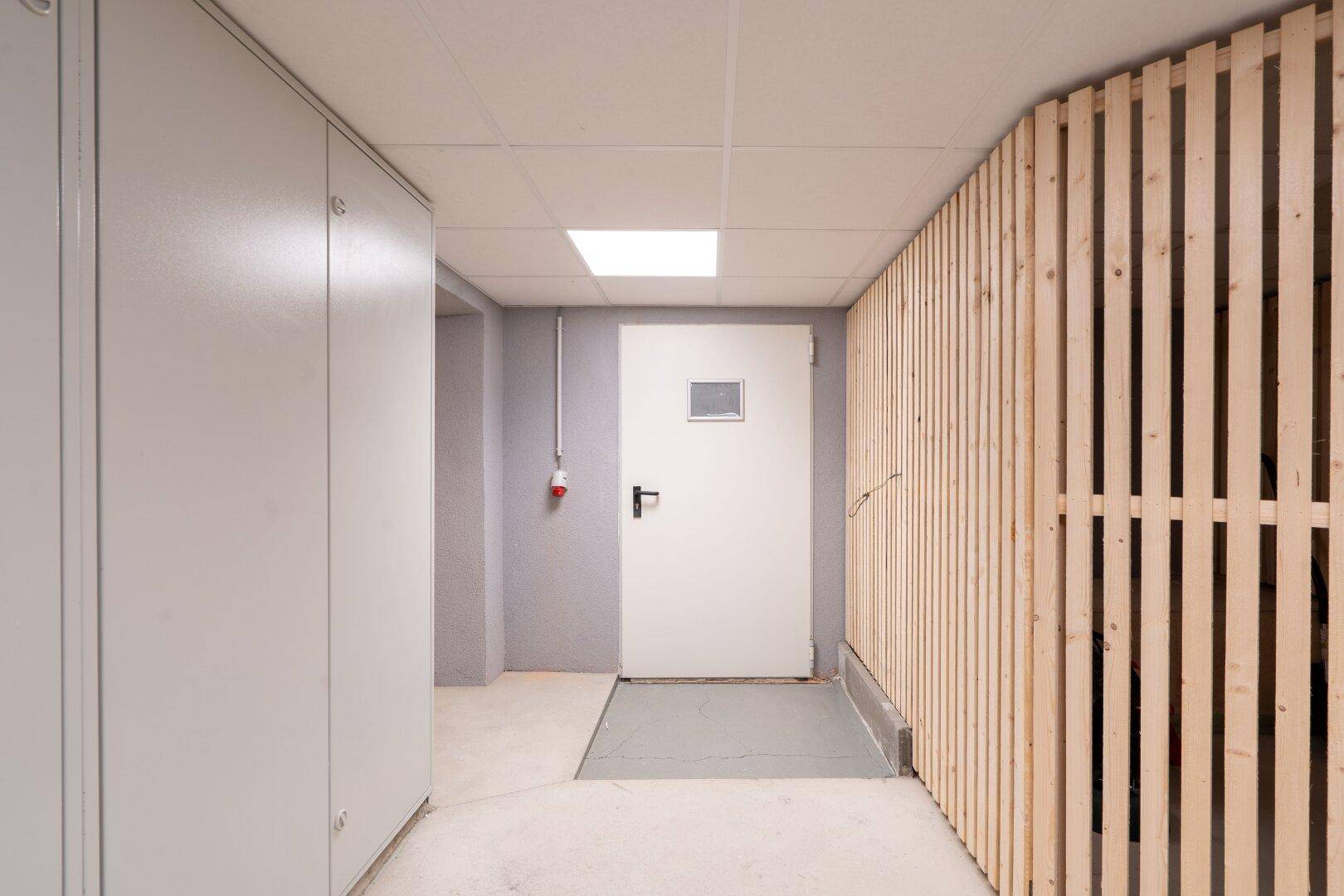 Kellerraum mit Holztrennwänden und einer Sicherheitstür, ideal für zusätzlichen Stauraum.