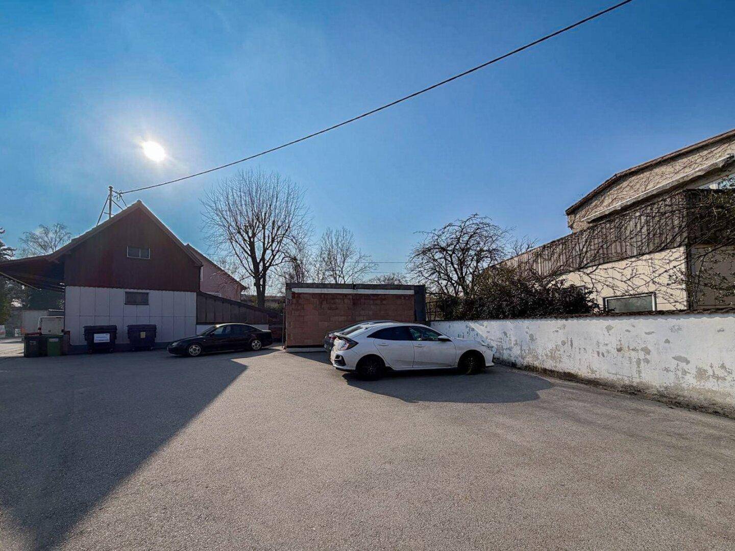 Außenansicht des Grundstücks mit Parkplätzen und Gebäuden unter strahlendem Sonnenschein.