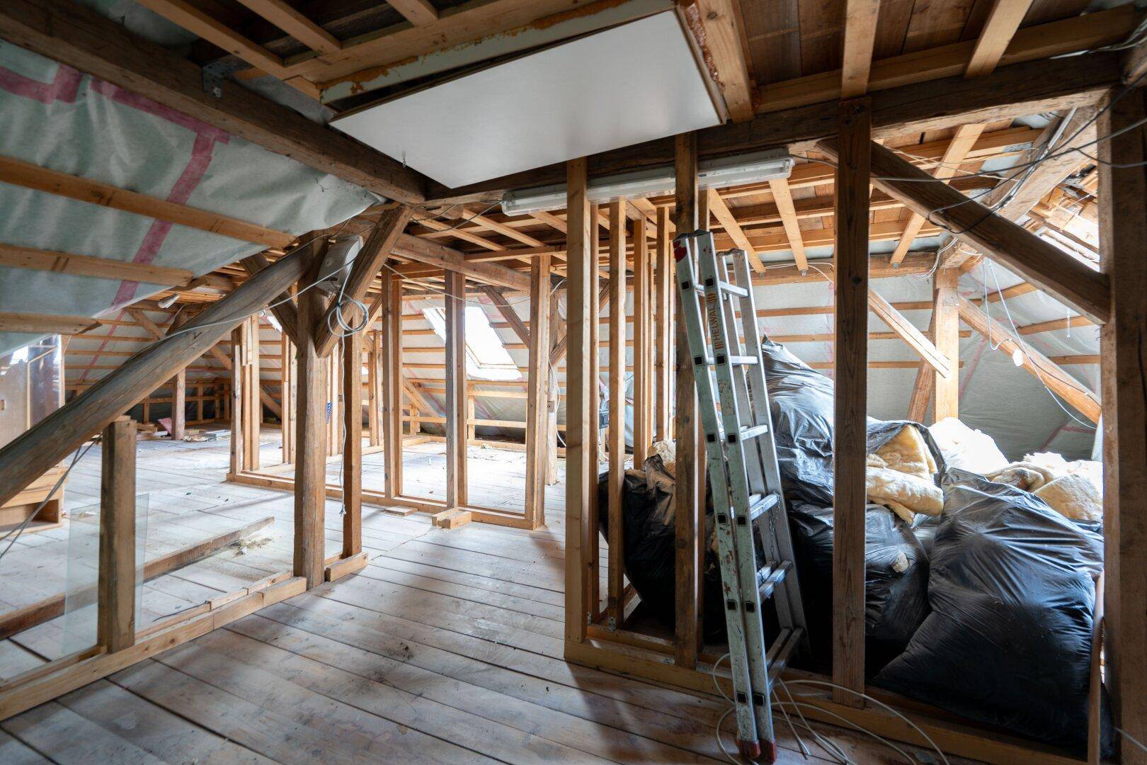 Dachgeschoss im Rohbau mit sichtbarer Holzkonstruktion und Dämmmaterialien, bereit für den Ausbau.