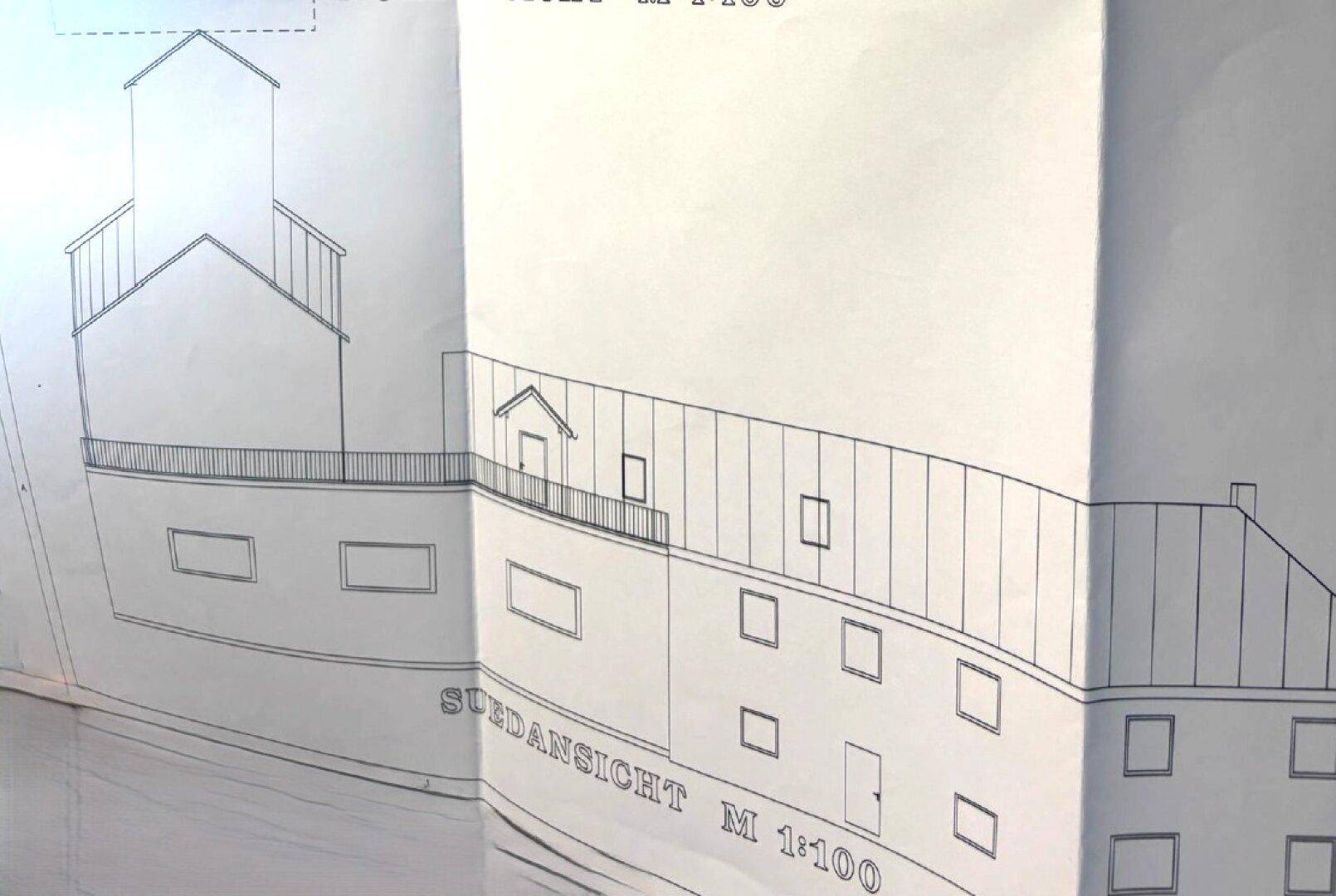 Südansicht des Gebäudes im Maßstab 1:100, zeigt die Fassade mit Balkon und Fenstern.