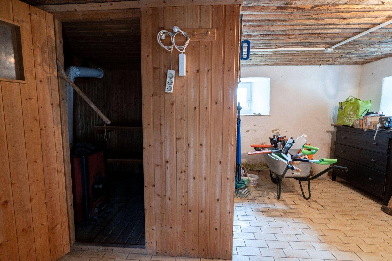Mehrzweckraum mit integrierter Sauna und gefliestem Boden, bietet Wellness-Möglichkeiten.