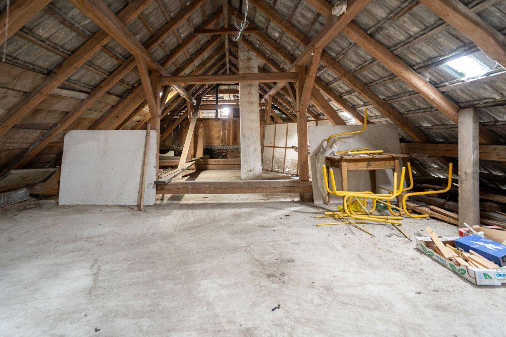 Geräumiger Dachboden mit sichtbarer Holzkonstruktion und Dachfenster, ideal für Ausbau.