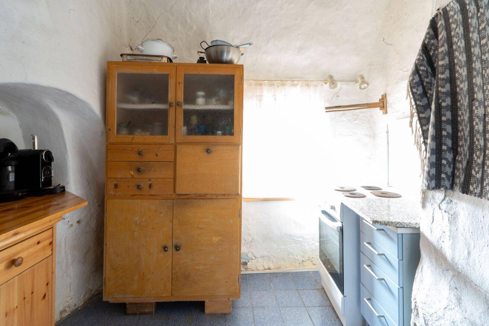 Einfache Küche mit Holzschrank, Granitarbeitsplatte und rustikalen Steinwänden.
