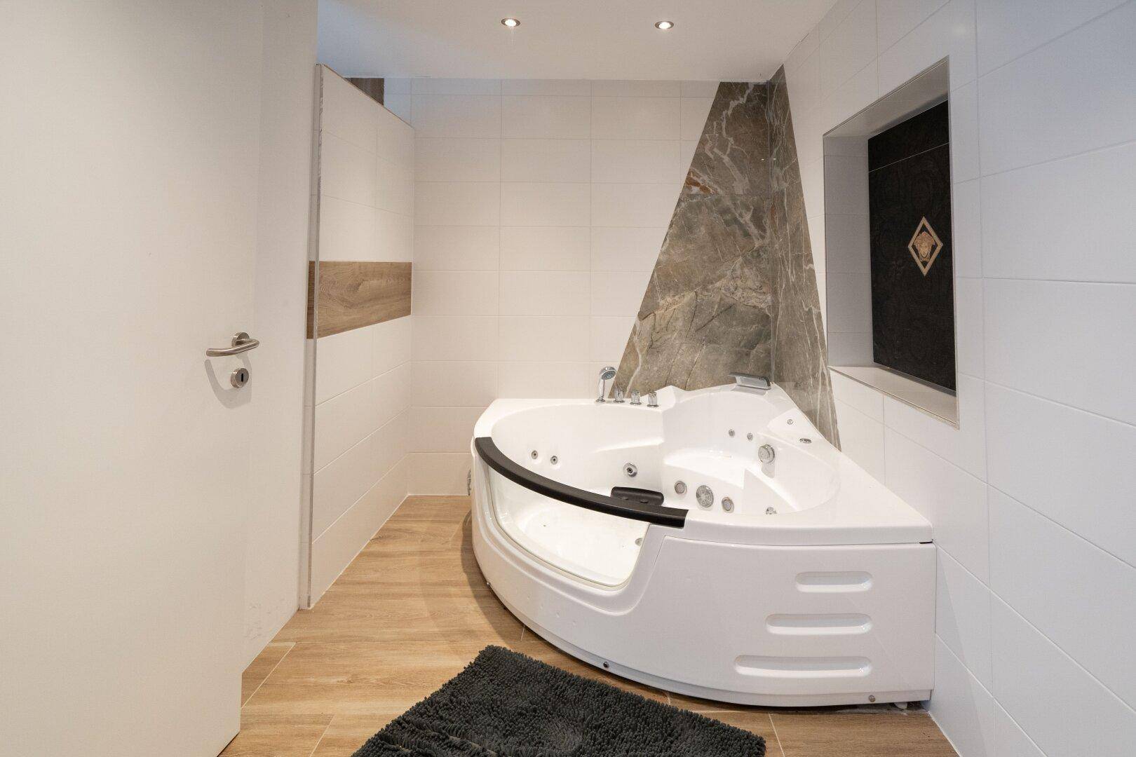 Luxuriöses Badezimmer mit Eckbadewanne und modernen Fliesen, das zum Entspannen einlädt.