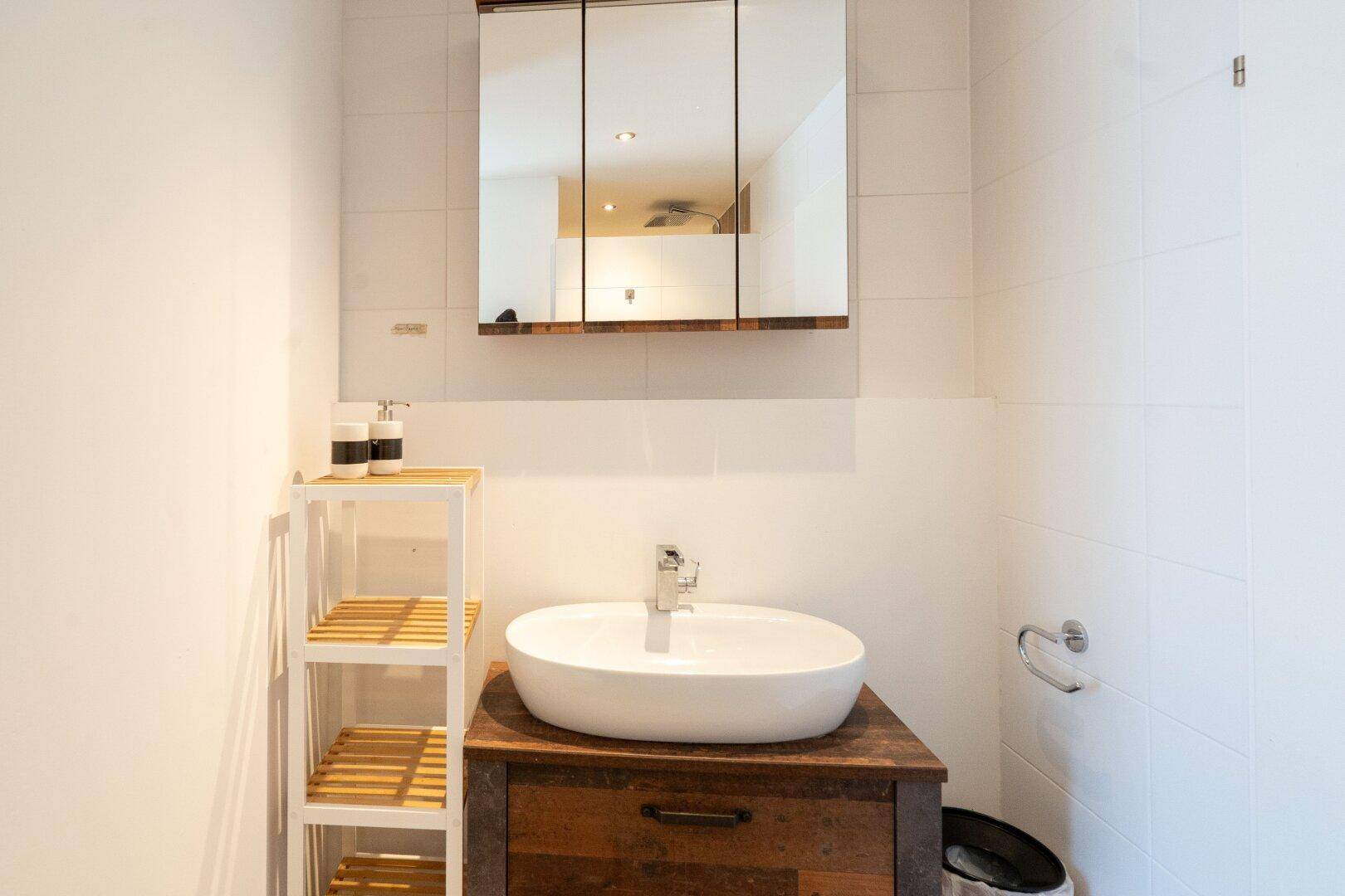 Modernes Badezimmer mit Aufsatzwaschbecken und Spiegelschrank, das eine helle und funktionale Einrichtung bietet.