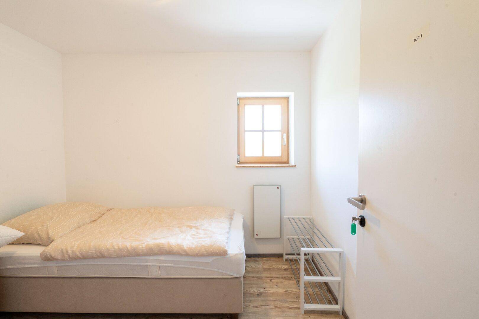 Gemütliches Schlafzimmer mit Einzelbett und Holzboden, das eine ruhige Atmosphäre schafft.